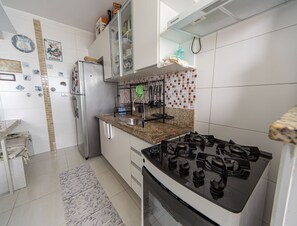 Een keuken met een gasfornuis, een koelkast van roestvrij staal en witte kasten.