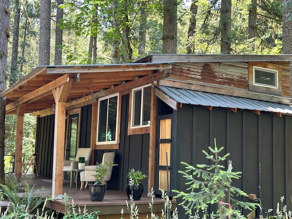 A cabin with a porch, wooden deck, and potted plants.