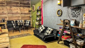 A cozy living room with a sofa, a red chair, a coffee table, a bookshelf, and a TV mounted on the wall.