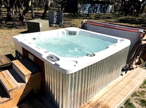 A hot tub on a wooden deck with steps leading up to it. - Cozy Glamping Yurt with Wildlife Views near Mountain Home, Texas (Mountain Home)