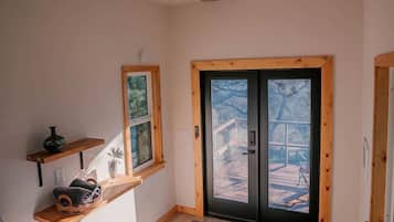 A bedroom with a bed, a window, a door, and a ceiling fan.