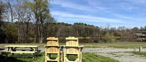 A picnic area with a table and two chairs, surrounded by grass and trees.