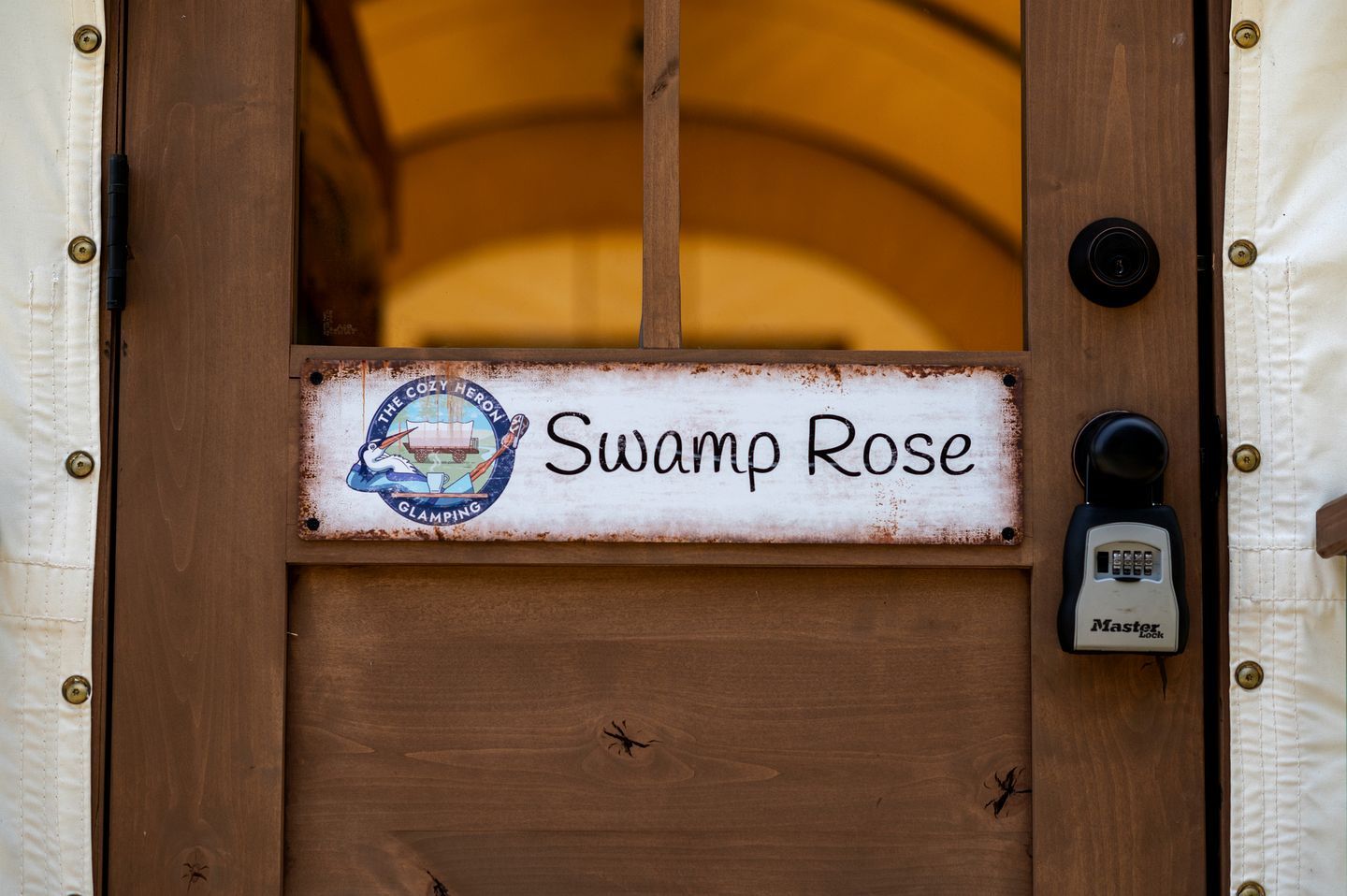 Una puerta de madera con un letrero que dice 'Swamp Rose' y un candado Master Lock.