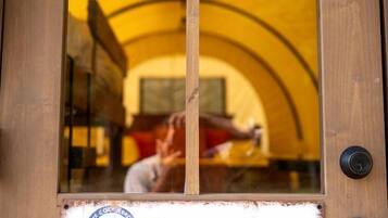 A wooden door with a sign reading 'Swamp Rose' and a view of a yellow tented area inside.