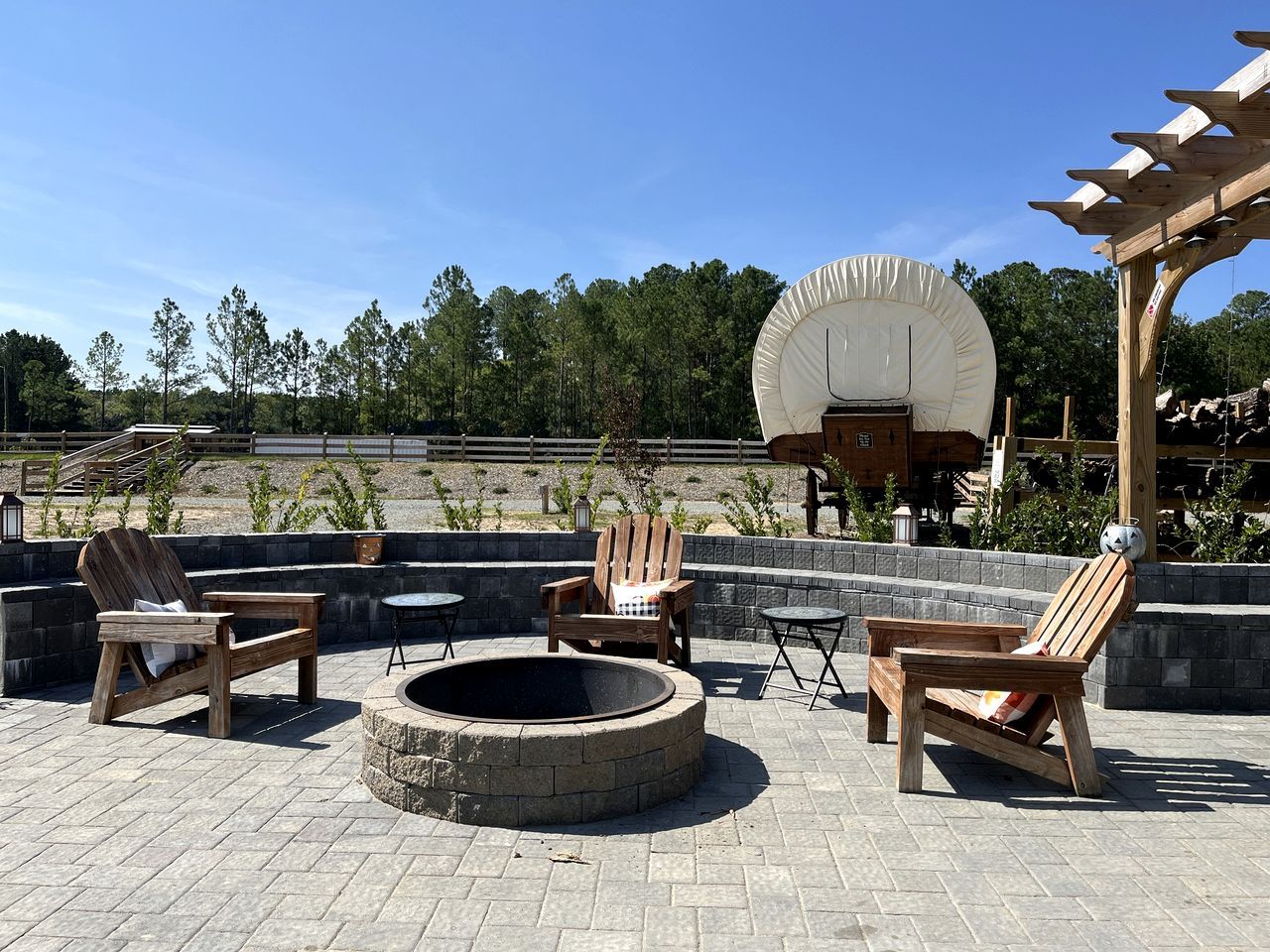 Un área de estar al aire libre con sillas Adirondack, una chimenea y una pérgola.