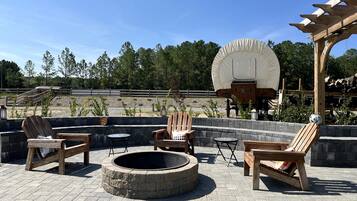 Un área de estar al aire libre con sillas Adirondack, una chimenea y una pérgola.
