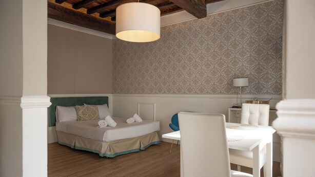 Een slaapkamer met een bed, nachtkastje en een lamp.