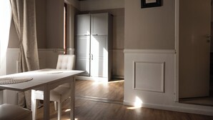 Een kamer met een eettafel, een stoel, een wit kastje en een deur naar een andere kamer.