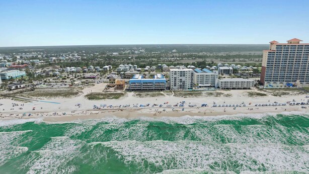 Un hotel frente al mar con varias construcciones, una playa y olas oceánicas.