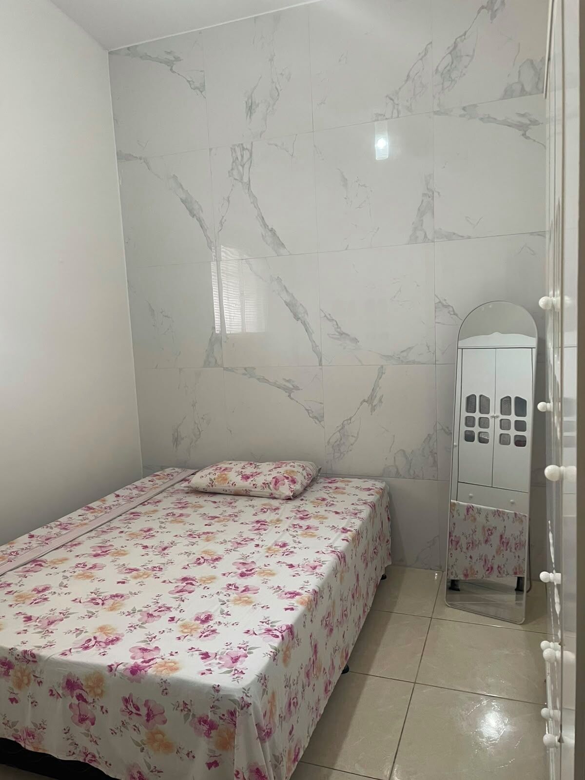 A bedroom with a bed, a vanity with a mirror, and a wardrobe.