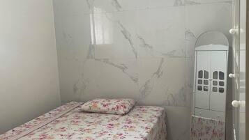 A bedroom with a bed, a vanity with a mirror, and a wardrobe.