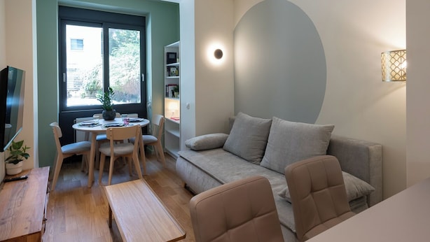 En moderne stue med sofa, spisebord og fjernsyn.