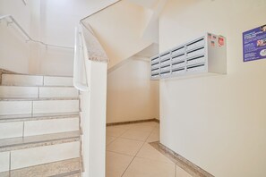 Eine Treppe führt zu einer Zwischenebene mit einer weißen Wand und einem Metallschrank.