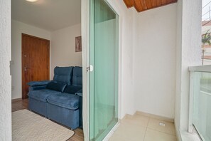 Ein Zimmer mit blauem Sofa, einer Schiebetür aus Glas, einer Holztür und einer weißen Wand.