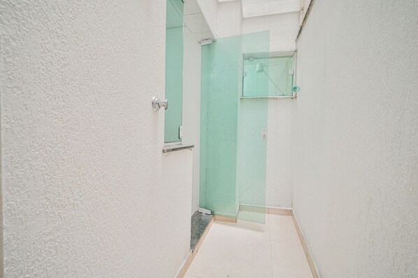 A narrow hallway with a green door leading to a bathroom.