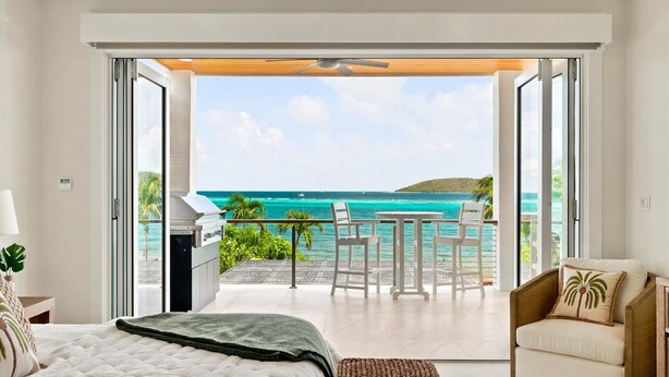 Un dormitorio con cama, una silla, una mesa y vistas al océano.