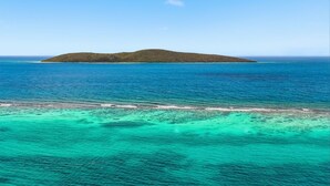Una vista despejada de un mar turquesa con una pequeña isla a lo lejos.