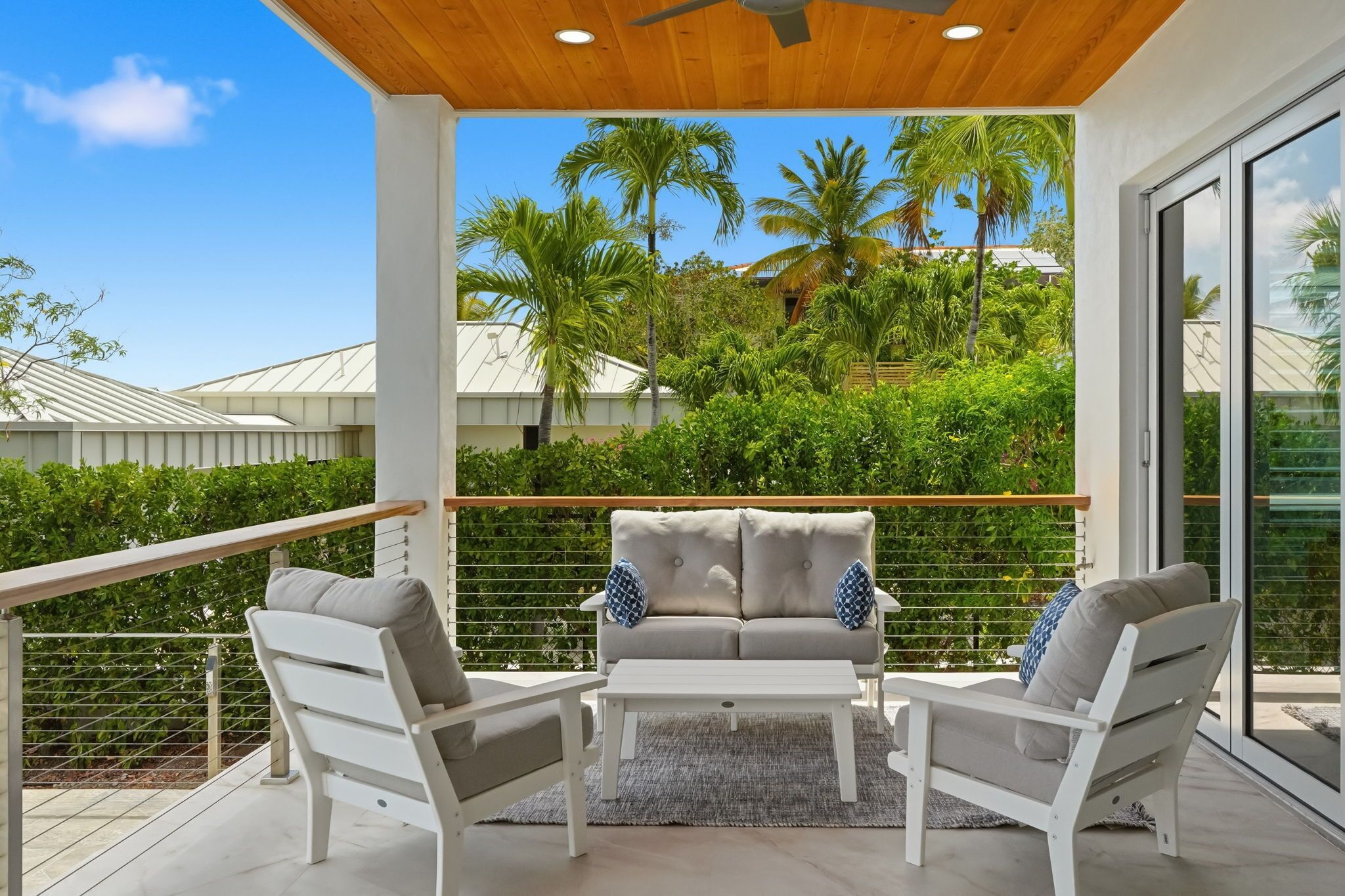 A balcony with a white sofa, two white chairs, and a small table.