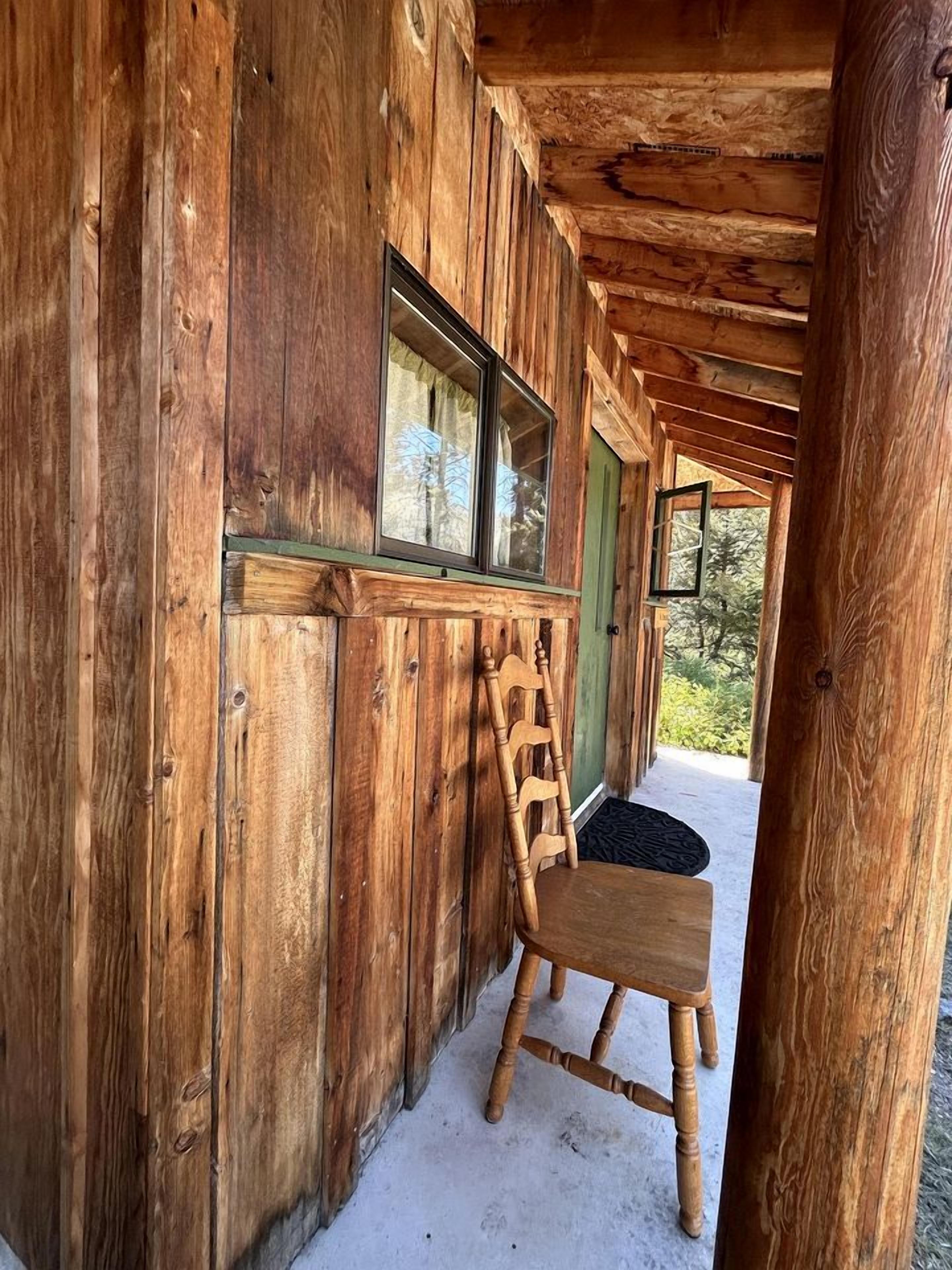 Una cabaña de madera con una silla de madera frente a una ventana.