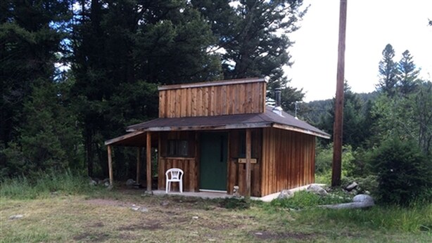 A rustic wooden cabin with a porch and a chair outside. - Secluded Family-Friendly Log Cabin Rental for Families near Helena (Hall)