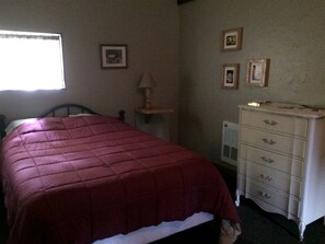 A bedroom with a bed, a dresser, and a window.