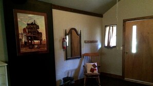 A room with a wooden door, a chair, a framed picture on the wall, and a mirror. - Secluded Family-Friendly Log Cabin Rental for Families near Helena (Hall)