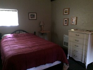A bedroom with a bed, a dresser, and a window.