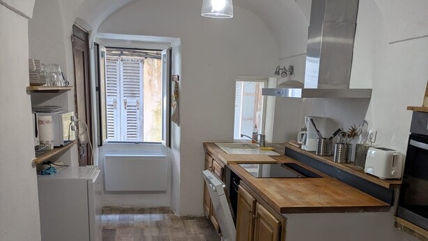 Une cuisine dotée d’un plan de travail en bois, de meubles blancs, d’un four encastré et d’un luminaire suspendu.