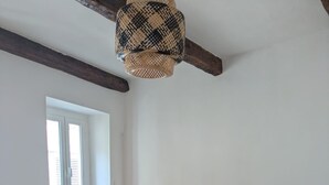 Une chambre à coucher avec une couvre-lit à motifs zébrés, une table de chevet en bois avec une lampe, une fenêtre avec des stores et un ventilateur de plafond.