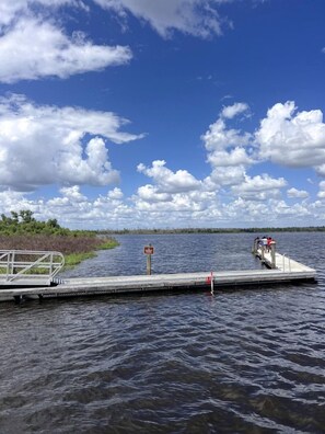 A dock extending into a body of water with a clear sky and clouds above. - Luxurious Deluxe Safari Tent with King Bed and Outdoor Fire Pit in Bradenton, Florida (Bradenton)
