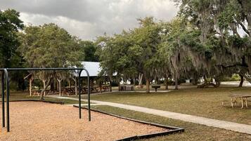 A park with playground equipment, picnic tables, and covered seating areas.