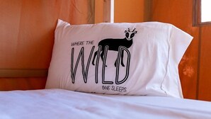 A bed with a pillow featuring a wild animal design and text.