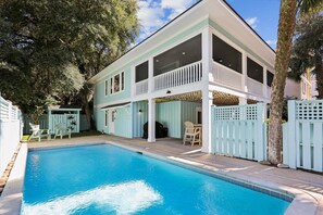 Ein zweistöckiges Haus mit Schwimmbad, überdachter Terrasse und einem umzäunten Garten.