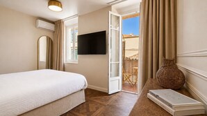 Hotelkamer met een bed, een flatscreen televisie, een rieten vaas en een tafel met boeken.