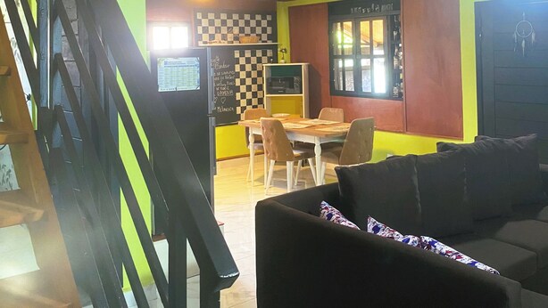 A multi-level interior with a staircase, a dining area with chairs and a table, and a sofa. - Cozy LOFT at NotAm Tour (Libreville)