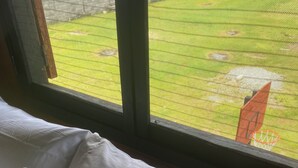 A bed with white bedding, a window with a view of a grassy area and a fence. - Cozy LOFT at NotAm Tour (Libreville)