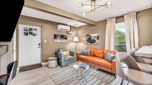 Een moderne woonkamer met een bank, fauteuils, een eettafel en een kroonluchter.