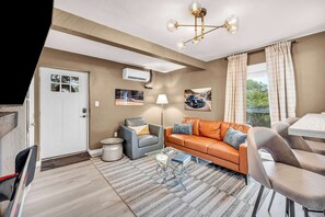 Ein modernes Wohnzimmer mit einer Couch, Sesseln, einem Couchtisch und einem Essbereich.