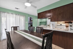 A dining area with a long table, chairs, and a kitchen with wooden cabinets. - Spacious Dallas Stay Near Downtown Attractions (Dallas)