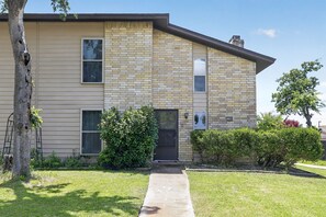 A two-story building with a brick facade, a front door, and a small front yard with a tree and bushes. - Spacious Dallas Stay Near Downtown Attractions (Dallas)