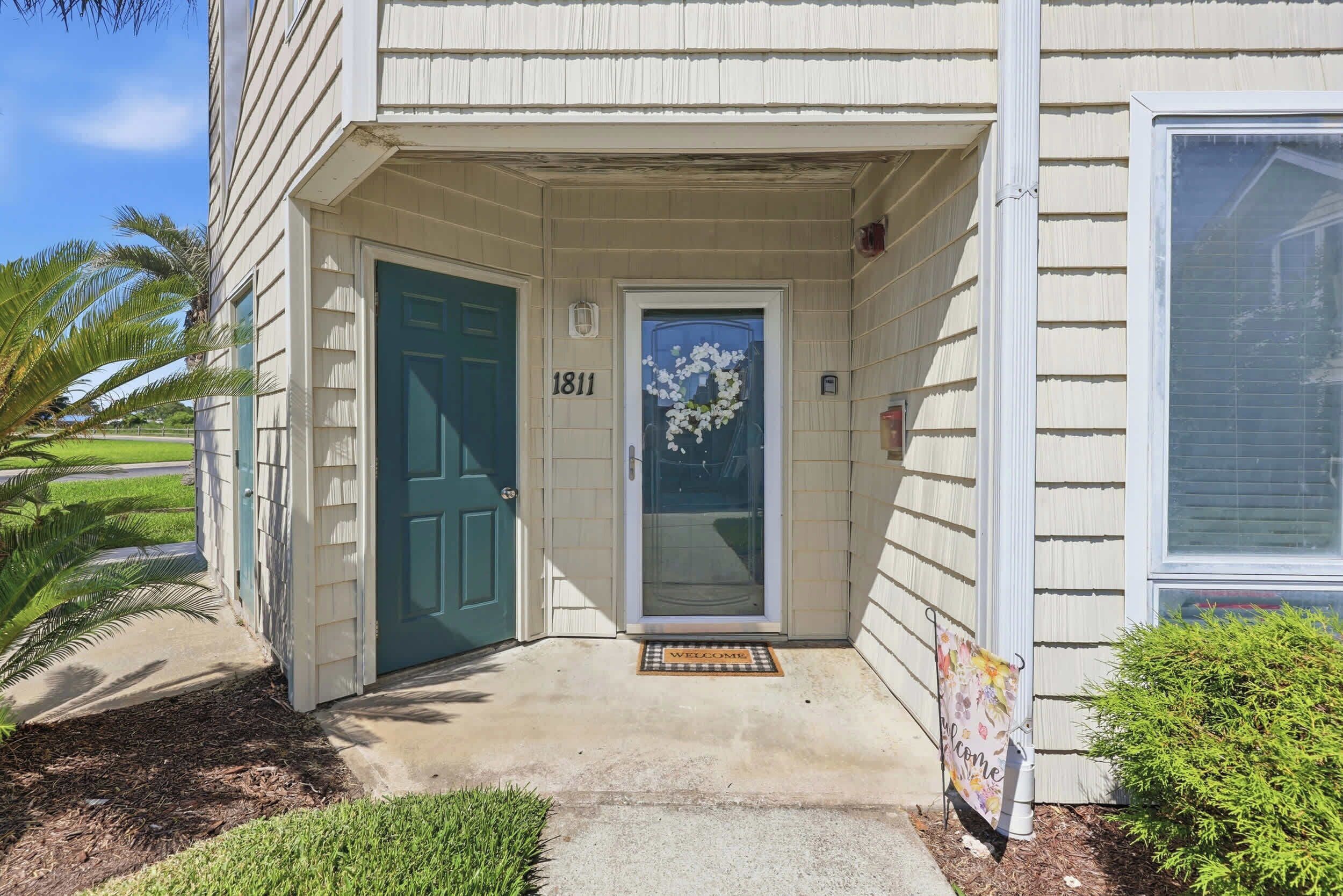 A house with a green door, a welcome mat, and the number 1811.