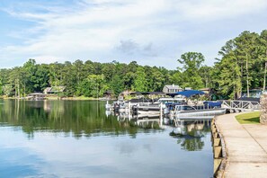 A lakeside dock with boats, a pier, and a row of houses with a dockside restaurant. - Modern Family-oriented 3BR 2BA Smart Home | Lake Martin Access | Near Auburn University (Tallassee)