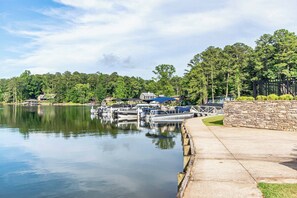 A marina with boats docked, a stone wall, and a grassy area.