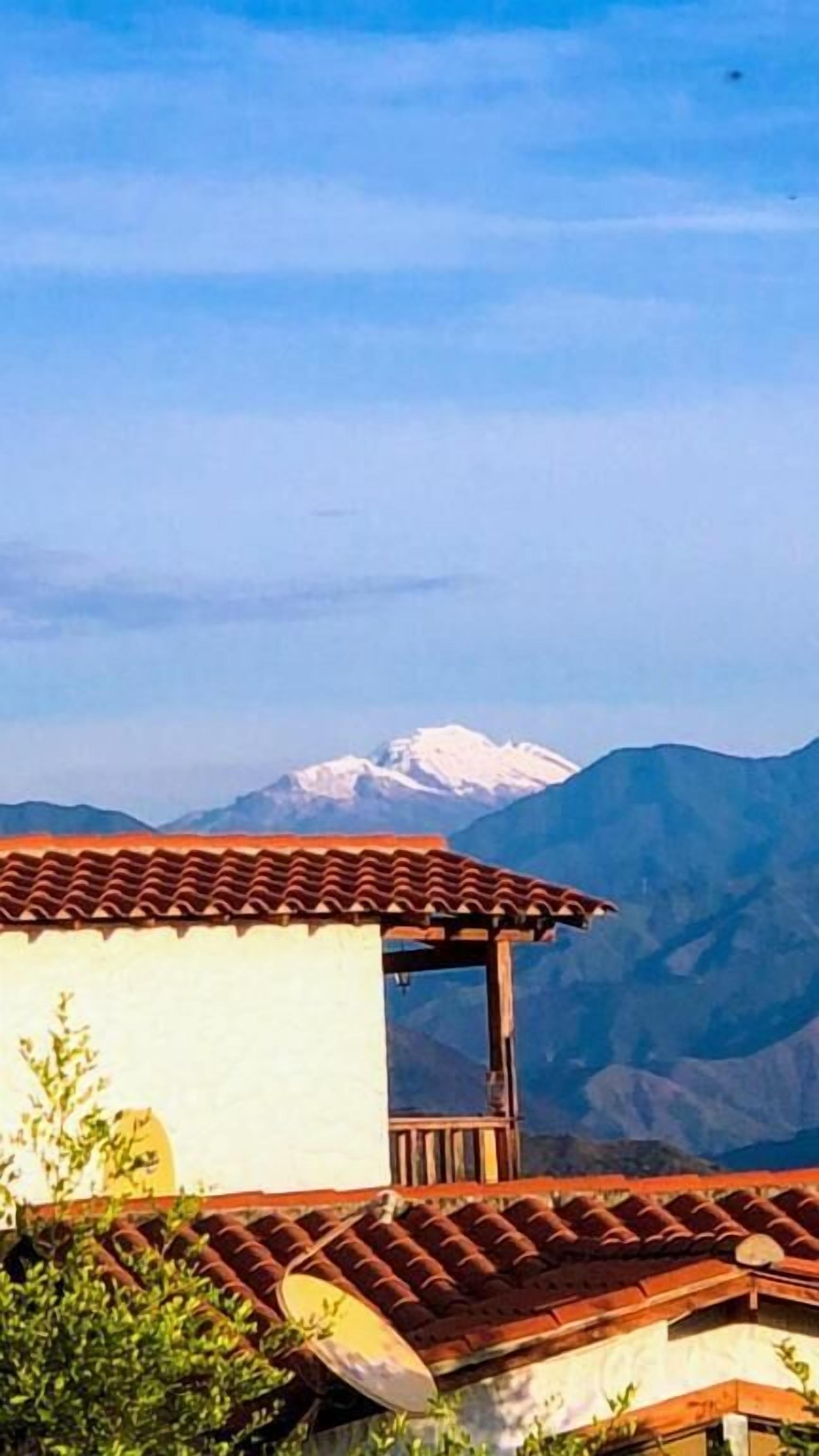 Un edificio con techo de tejas y vistas a montañas nevadas al fondo.