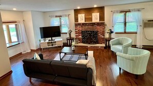 Un salon comprenant un canapé, des fauteuils, un téléviseur, une cheminée et un meuble pour téléviseur.