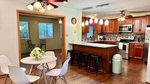 Une cuisine moderne avec des meubles en bois, un îlot central et un coin repas doté de chaises blanches.