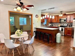 Une cuisine moderne avec des meubles en bois, un îlot central et un coin repas doté de chaises blanches.