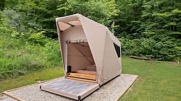 Una tienda portátil con una plataforma elevada y un espacio para dormir en su interior.