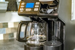 Una màquina de cafè amb pantalla digital i ampolla de vidre transparent.