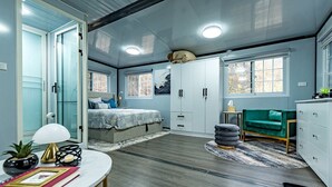 Een slaapkamer met een bed, een bureau, een stoel, een kledingkast en een raam.